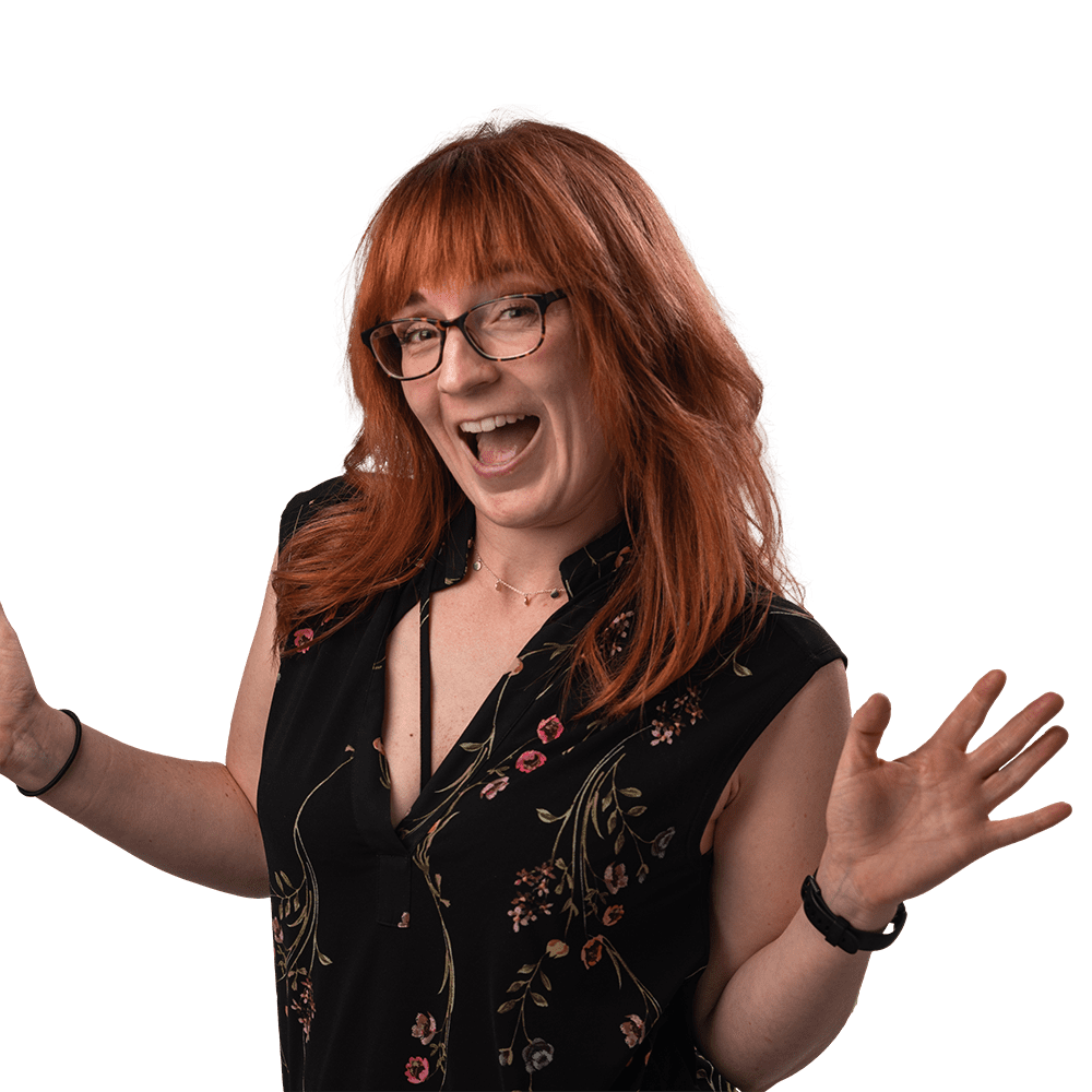 A Women with red hair and glasses with her mouth open looking happy